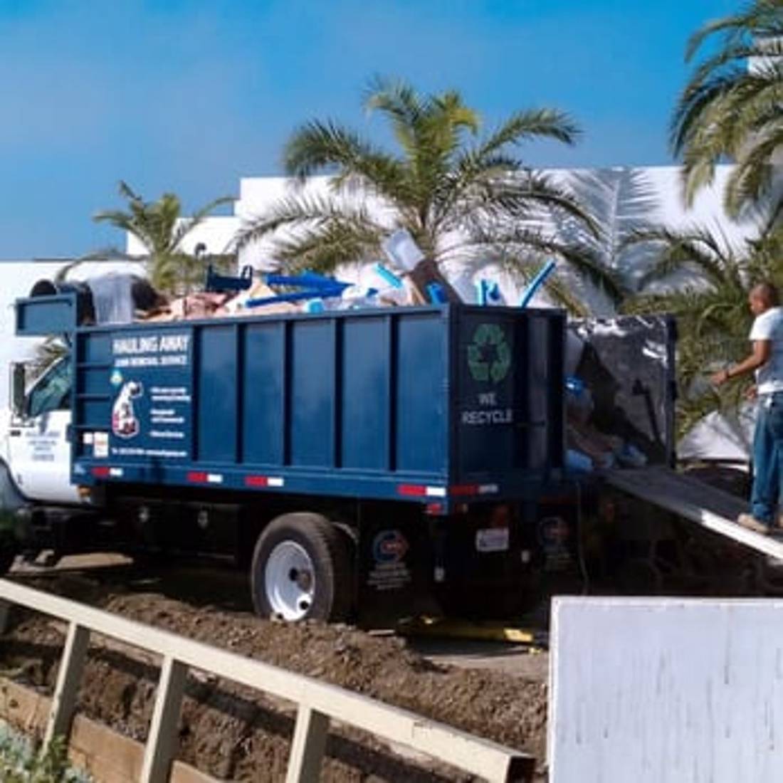 Rear of the Hauling Away truck marked We Recycle, loaded with junk